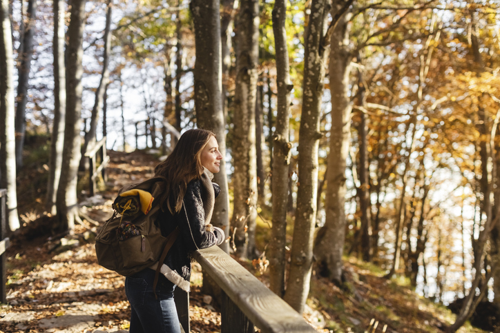 Vrouw staat tijdens een wandeling in het bos stil bij haar omgeving.
